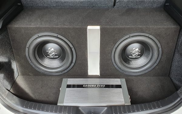 Twin Ground Zero subwoofers in a black carpeted enclosure with a Ground Zero amplifier in front of them