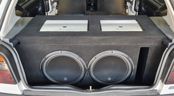 A twin subwoofer build in a white car, enclosed and carpeted, with the boot trim refitted